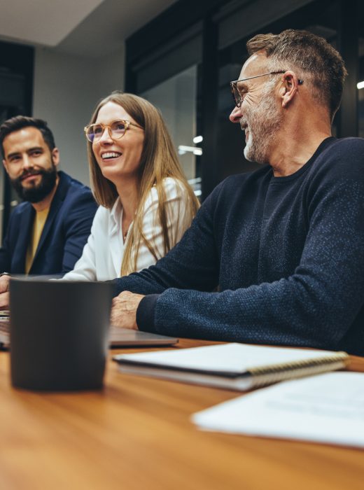 Successful group of businesspeople having a briefing in a boardroom. Happy businesspeople smiling while working together in a modern workplace. Diverse business colleagues collaborating on a project.